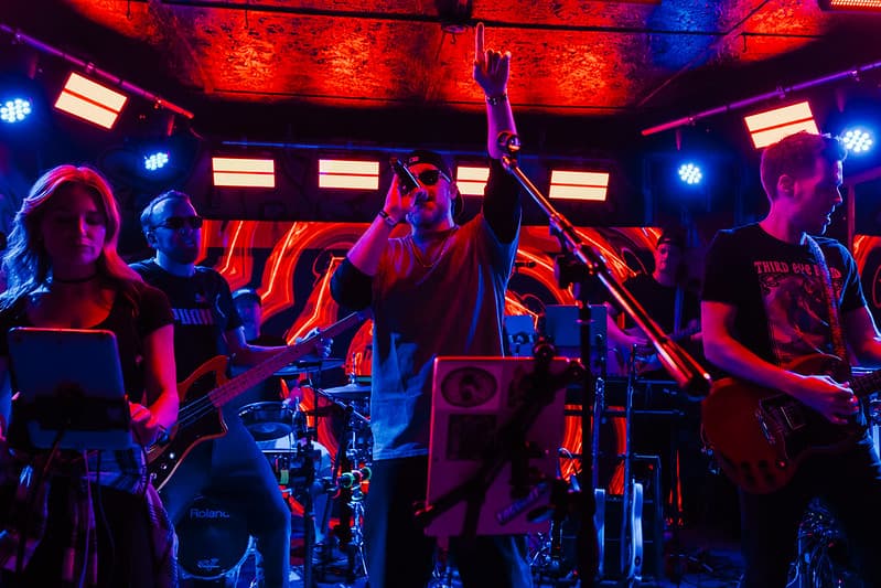 Full band performing under intense red and blue stage lights