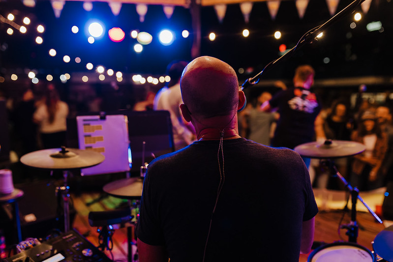 Band performing under string lights at an evening event